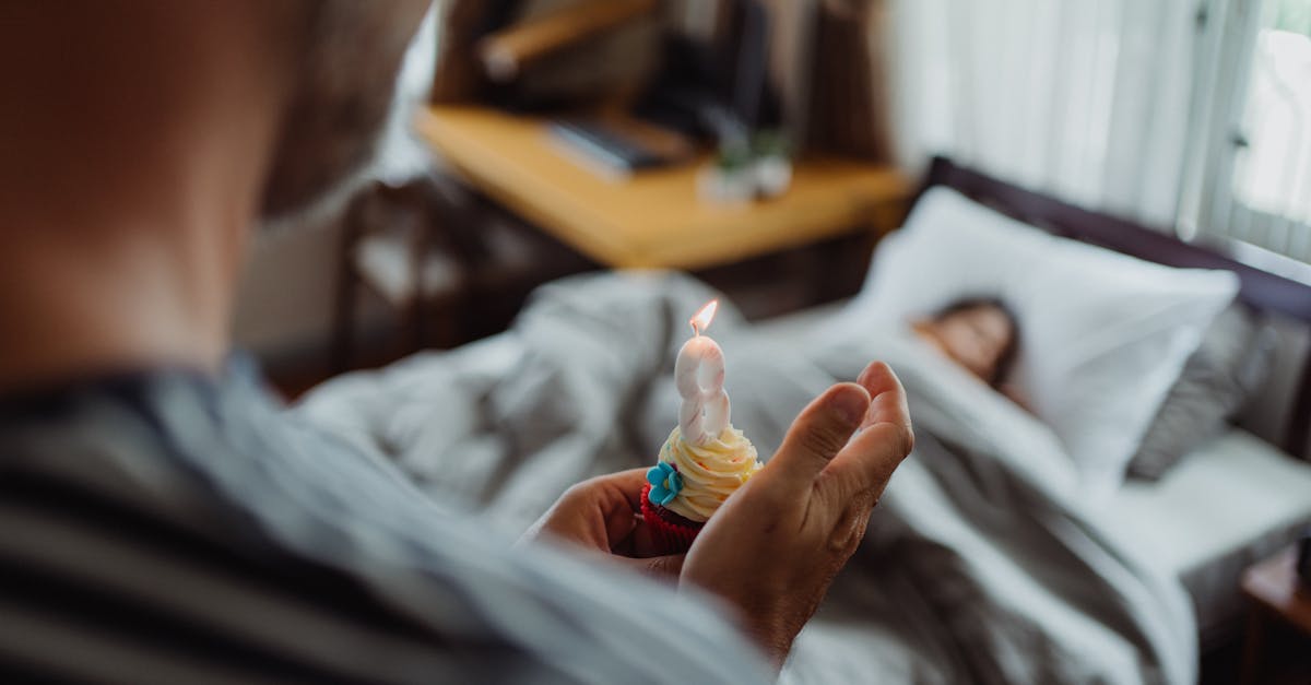 A father surprises his daughter in bed with a birthday cupcake. Morning celebration indoors.