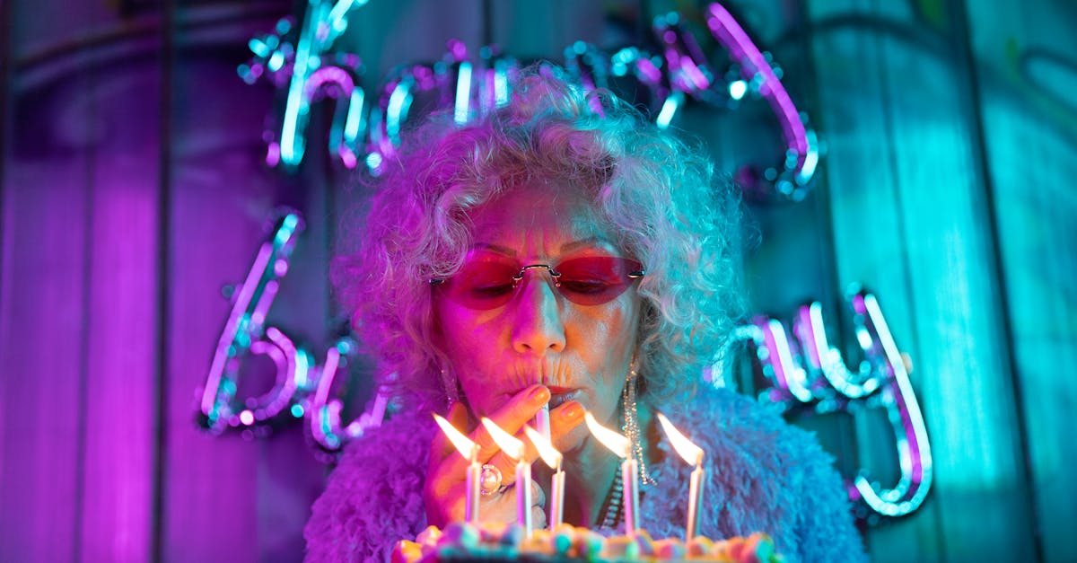 Trendy senior woman blowing out candles at a vibrant birthday celebration.