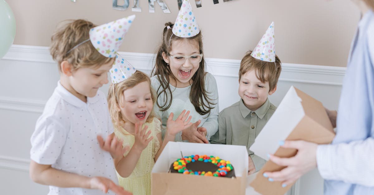 Joyful kids celebrating a birthday with a colorful cake and party hats indoors.