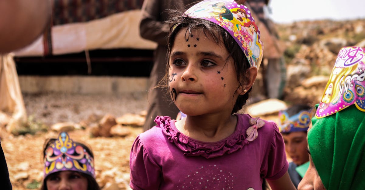 A joyful children's birthday party in Idlib, featuring face stickers and colorful hats with a festive atmosphere.