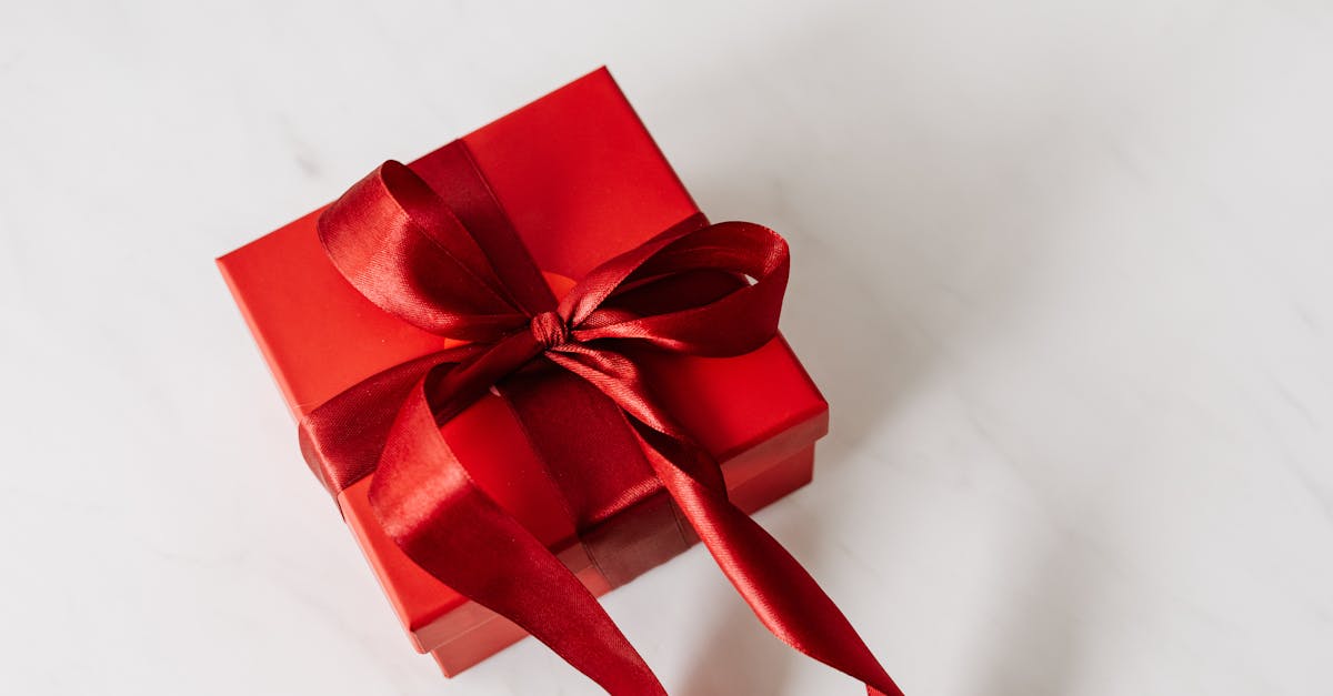 A red gift box with a satin ribbon, perfect for celebrations on a marble background.