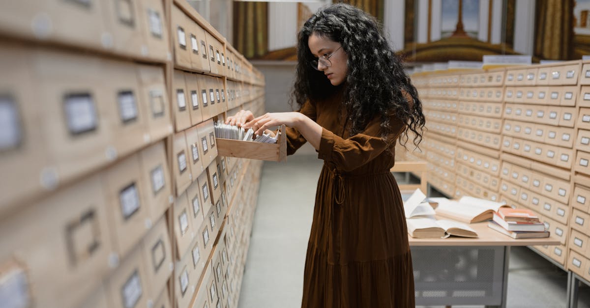 A woman browsing a card catalog in library archives, focusing on research and information gathering.