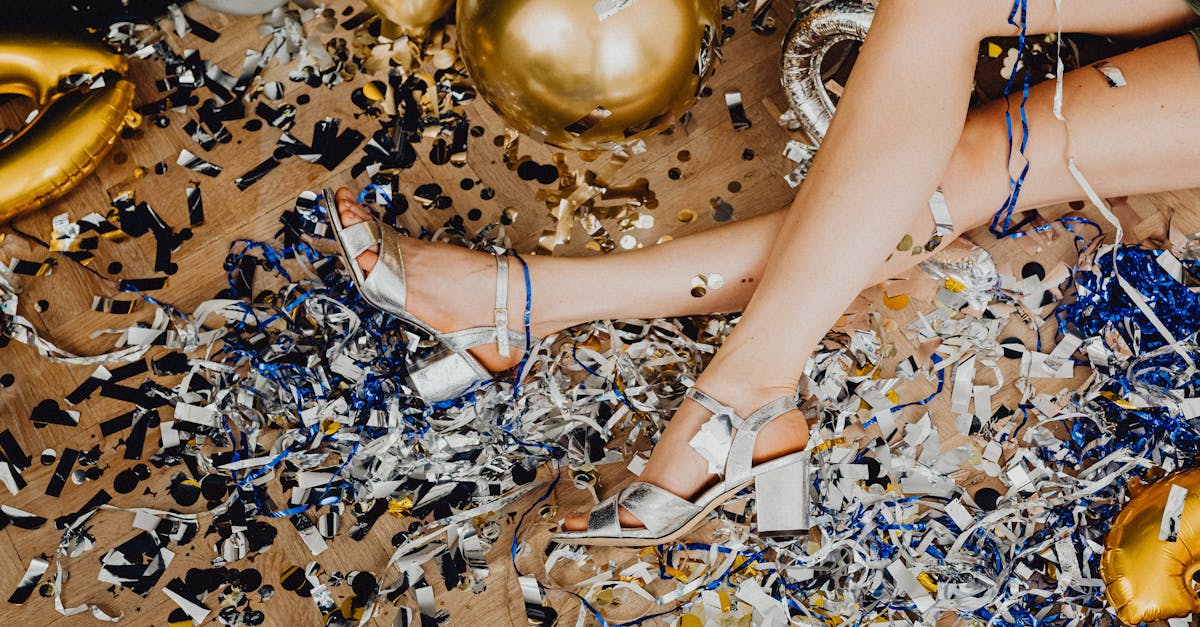 Elegant legs amidst a colorful mix of confetti and balloons, capturing a vibrant celebration aftermath.