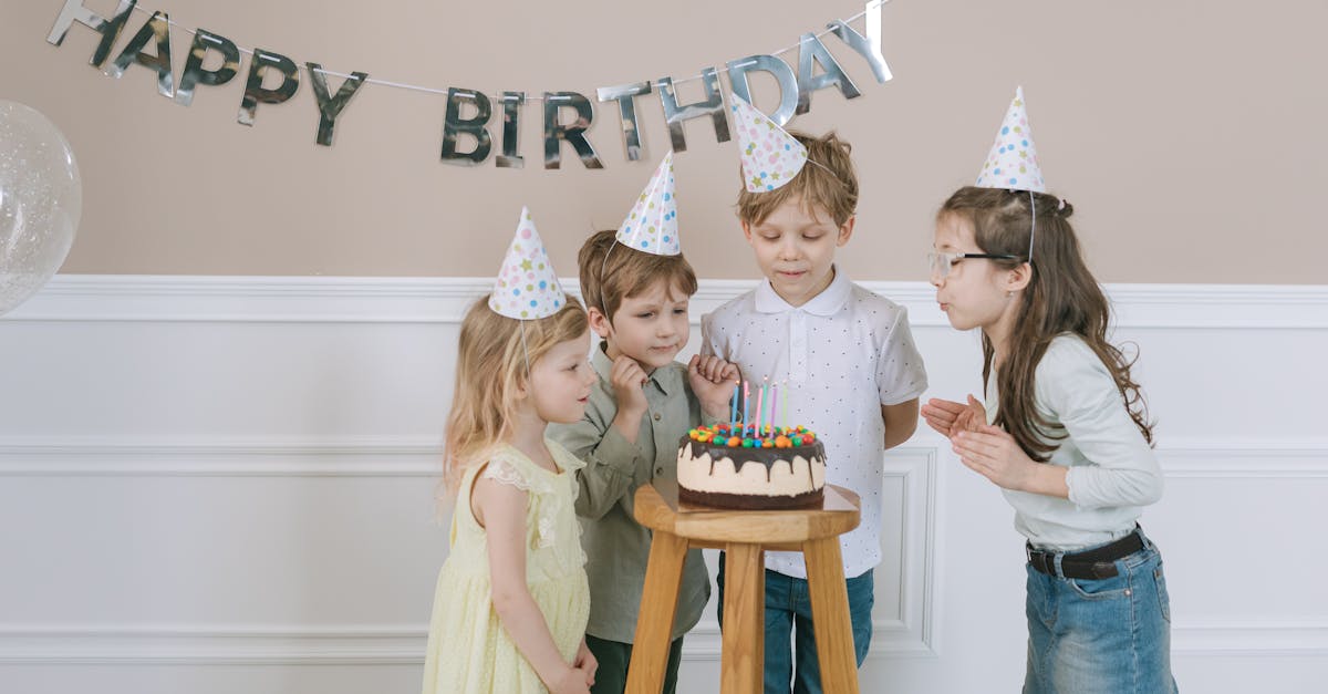 Group of children celebrating a birthday with cake and decorations indoors.