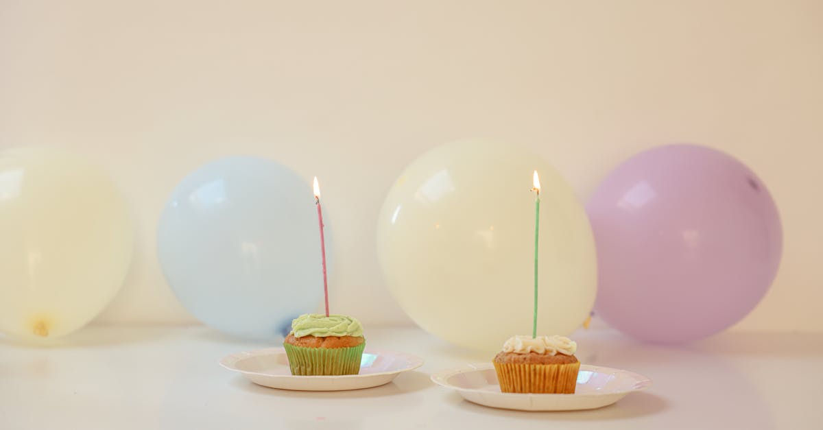 Vibrant cupcakes with lit candles surrounded by balloons, perfect for celebrations.