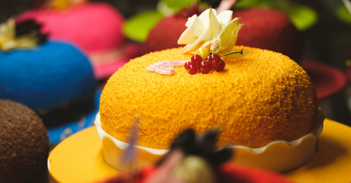 Vibrant display of assorted cakes adorned with fresh flowers and berries in a bakery.