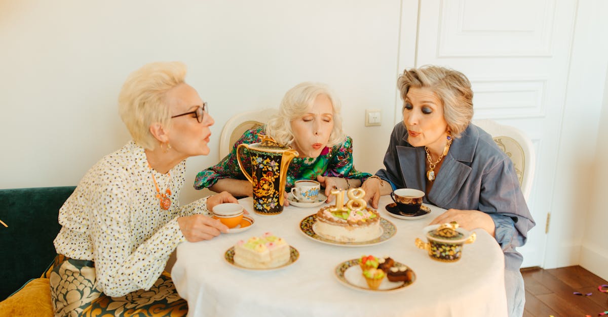 Three senior women celebrate a birthday indoors with cake and tea. A joyful celebration of life and friendship.