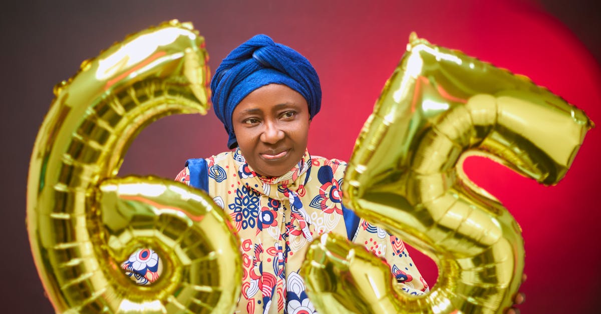 Senior woman celebrating 65th birthday with golden balloons indoors.