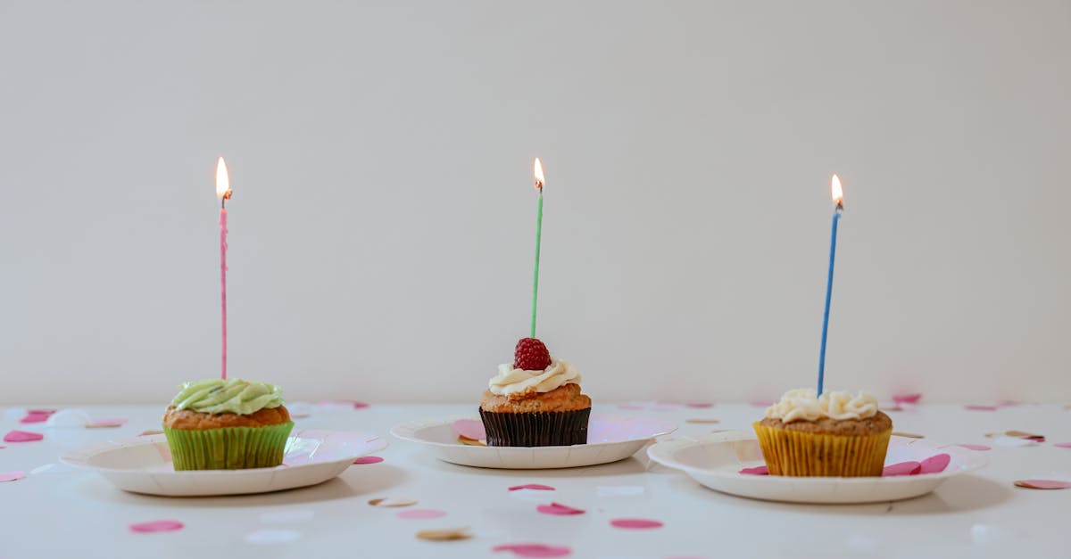 A festive arrangement of cupcakes with lit candles surrounded by confetti for a cheerful birthday celebration.