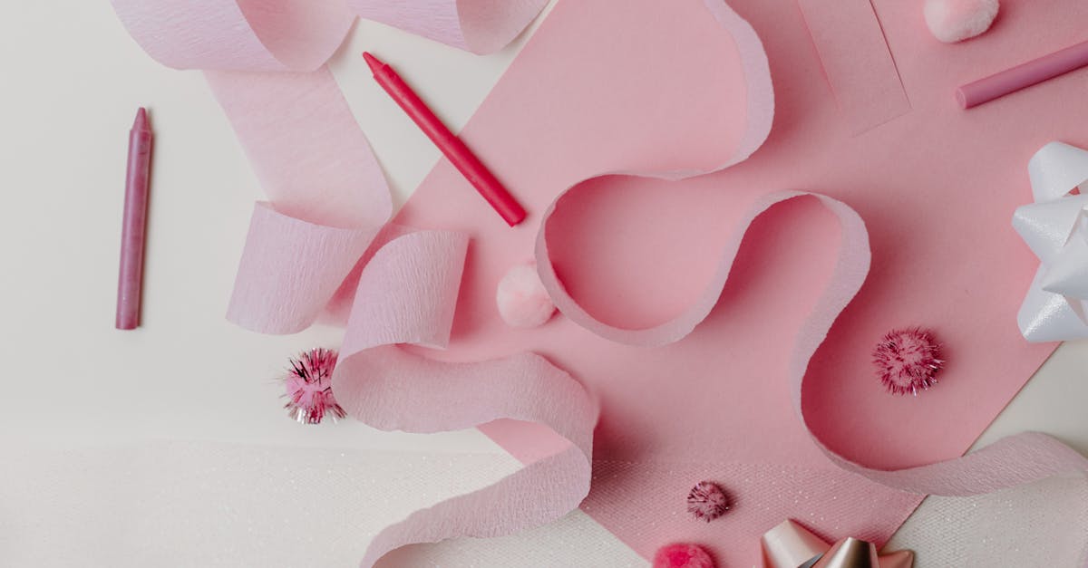 Flat lay of pink craft supplies and decorations featuring ribbons and bows on a pastel background.