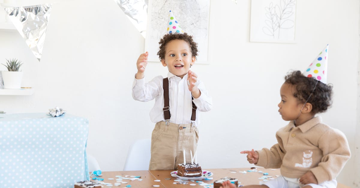 Two kids celebrating a birthday party with cake and decorations indoors.